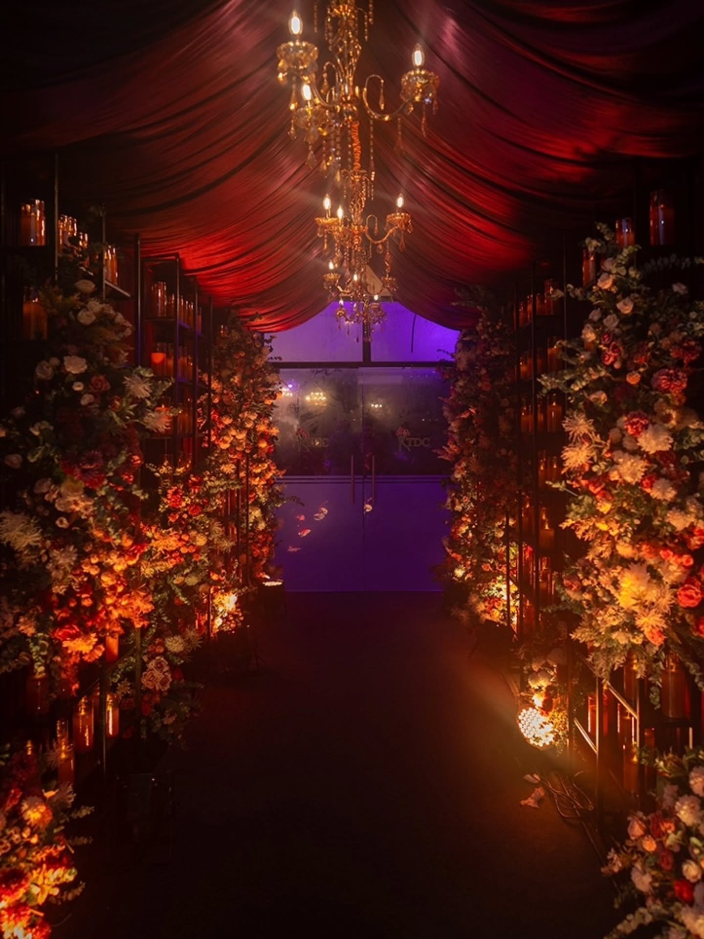 Immersive floral event entrance with chandeliers and candlelight